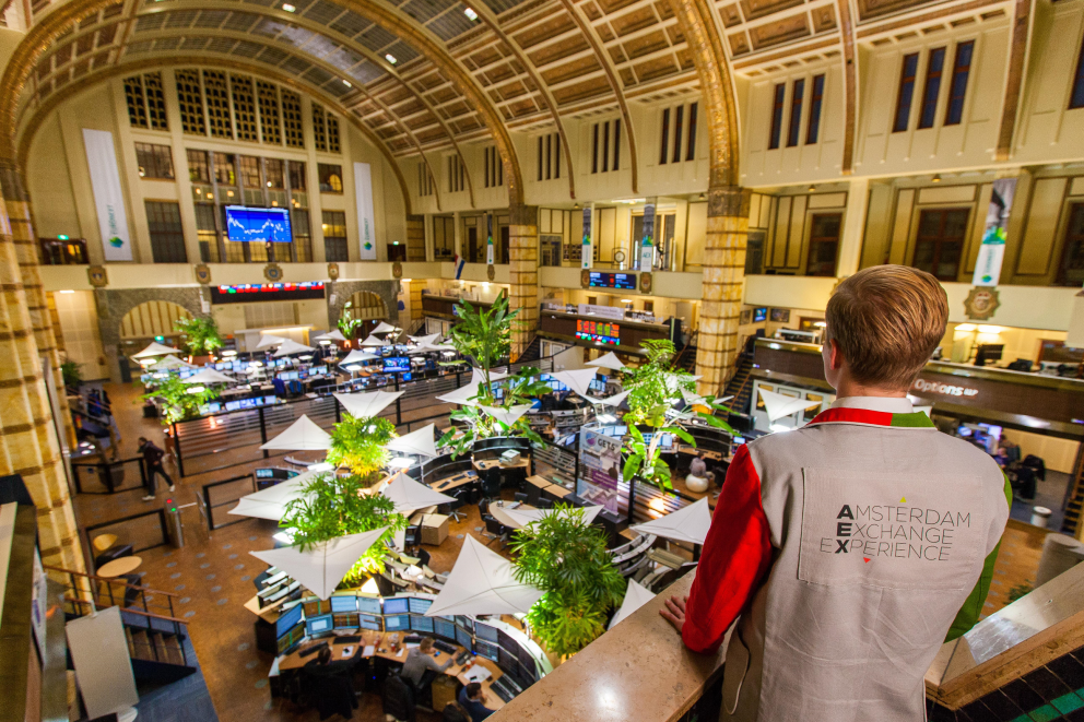 man met Amsterdam Exchange Experience jas kijkt over de vloer van de Beurs van Berlage